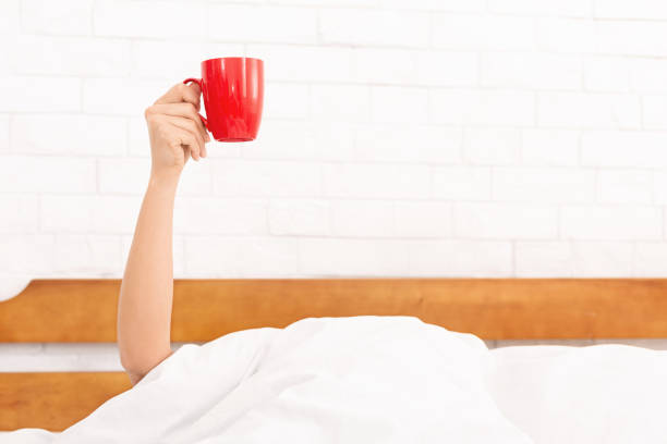 istock Female hand raised up coffee cup in bed 1140144206