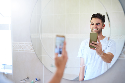 Shot of a young man taking selfies in the bathroom at home