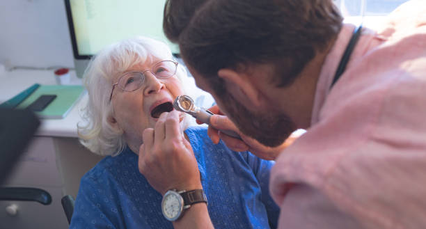 male doctor checking senior female patient mouth with otoscope - doctor patient male tongue depressor imagens e fotografias de stock