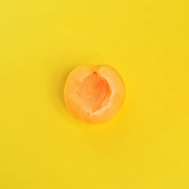 birnenhälften auf gelbem hintergrund. in eine halbe aprikose schneiden. pastellfarben, minimale trendige konzeptkunst. top view. flat-lay. - nectarine peaches peach abstract stock-fotos und bilder