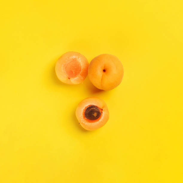 mitades de pera sobre un fondo amarillo. cortado en albaricoque medio y medio. colores pastel, arte conceptual minimalista de moda. vista superior. lay plano. - nectarine peaches peach abstract fotografías e imágenes de stock