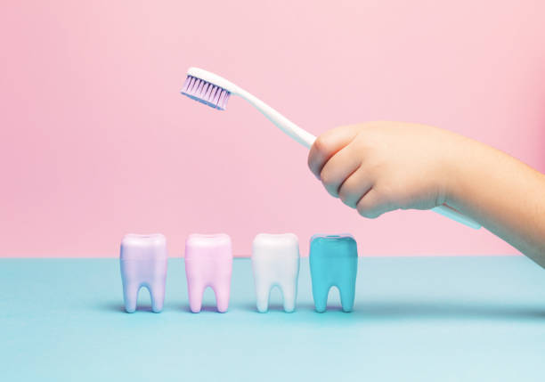 Child's hands holding big tooth and toothbrush Child's hands holding big tooth and toothbrush on pink backgroubd. Healty care teeth concept. Top view, flat lay. Copy space for your text. dental equipment hand stock pictures, royalty-free photos & images