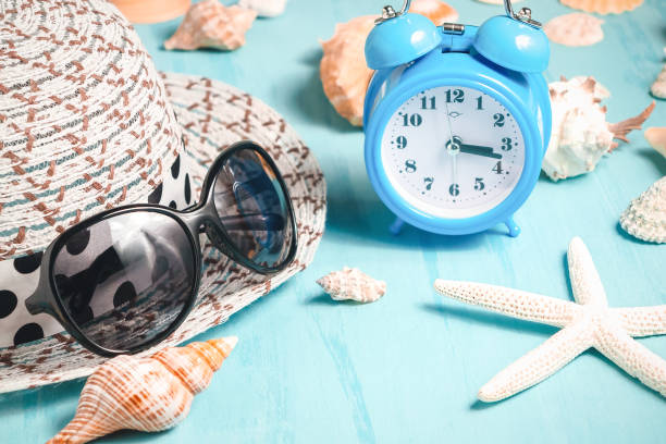 istock Seashells, alarm clock and beach accessories on a blue table - summer vacation and vacation time concept 1140150324