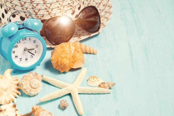 istock Seashells, alarm clock and beach accessories on a blue table - summer vacation and vacation time concept 1140150326
