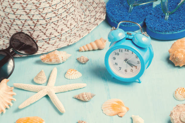 istock Seashells, alarm clock and beach accessories on a blue table - summer vacation and vacation time concept 1140150337