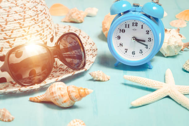 istock Seashells, alarm clock and beach accessories on a blue table - summer vacation and vacation time concept 1140150363