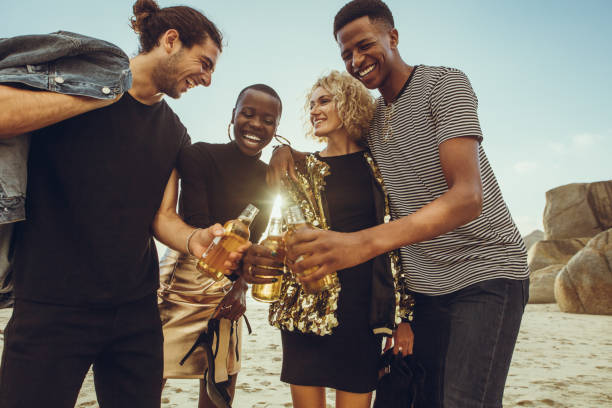 mehrethnische gruppe von freunden, die bier am strand trinken - couple young adult african descent multi ethnic group stock-fotos und bilder