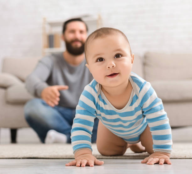 istock Adorable baby boy crawling on floor with dad 1140151669