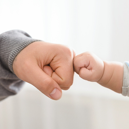 Big and little men connection. Father and baby son bumping fists, closeup