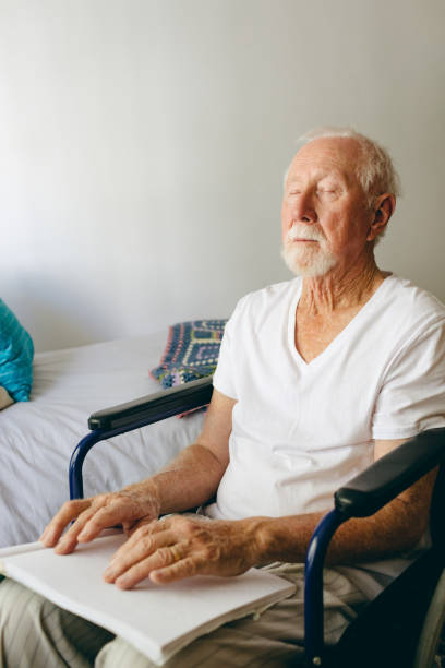 istock Blind senior man using braille to read in a retirement home 1140154468