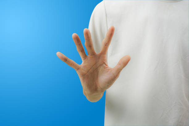 istock A white shirt man making stop gesture with his hand on blue background. 1140155059