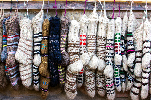 New knitted wool socks of different colors and ornaments hanging in a row