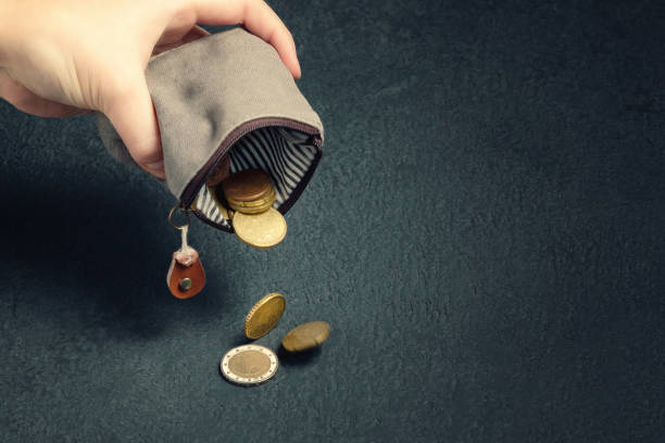 plusieurs pièces tombent sur la table d’un portefeuille vide dans la main d’une femme, la pauvreté, la crise, la faillite et le concept de problèmes financiers - small group of objects photos et images de collection