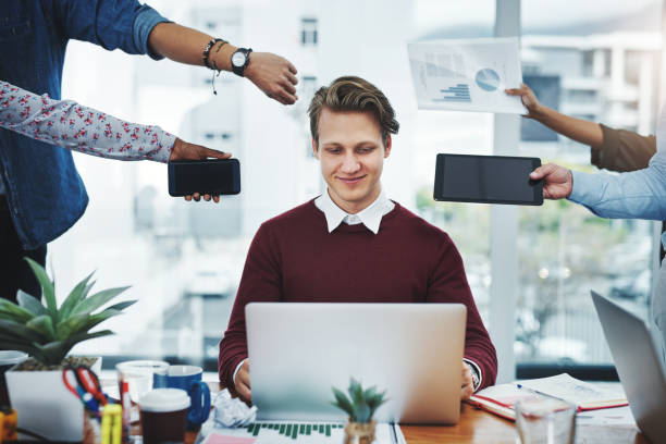 Staying cool under pressure Shot of a young businessman using a laptop in a demanding office environment delegating stock pictures, royalty-free photos & images