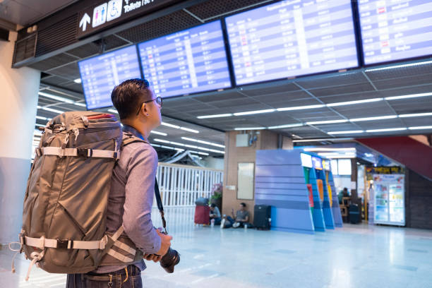 istock Asian young man with backpack in airport near flight timetable - Image 1140157331