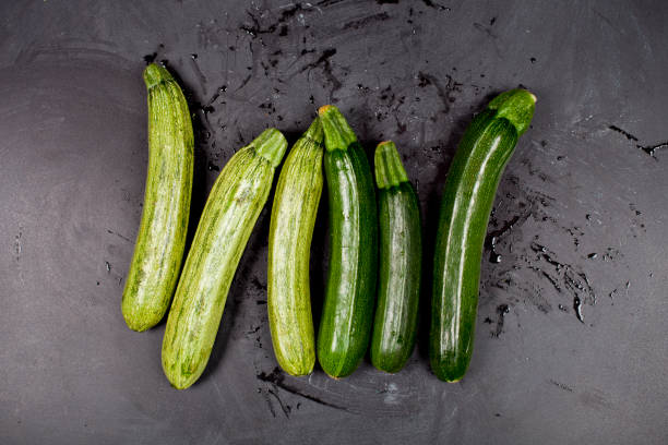 istock Fresh green wet zucchini on blackboard background. 1140157882