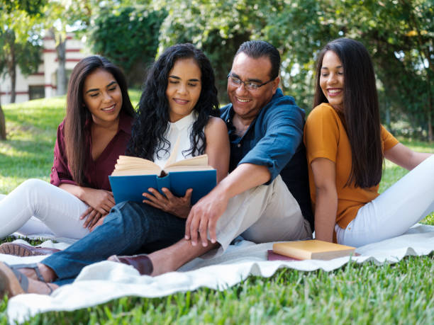 istock Latin family sitting outdoors reading a book together 1140158144
