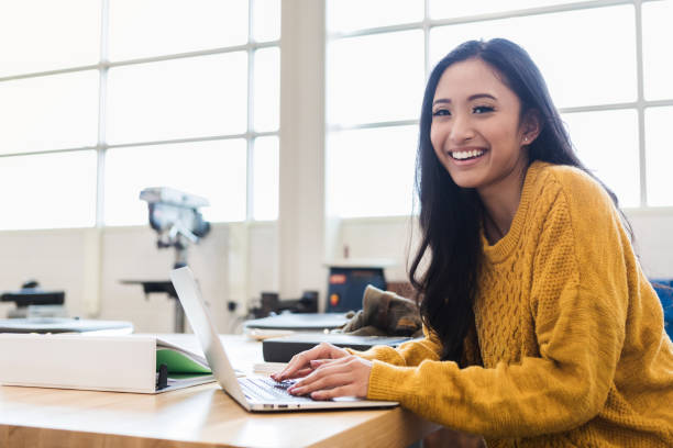Confident student using laptop Cute Asian teenage girl uses laptop in a science classroom or lab. She is smiling at the camera. back to school college stock pictures, royalty-free photos & images