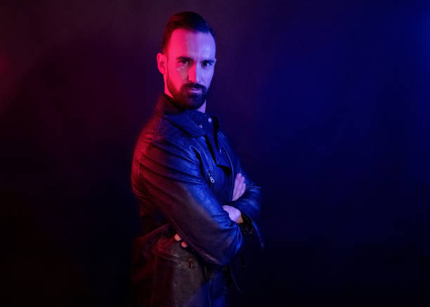 istock Handsome man wearing a leather jacket with blue and red gel lighting 1140164368