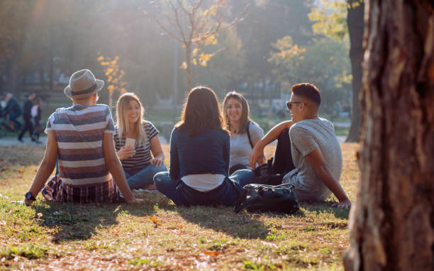 grupa pięciu przyjaciół śmieje się głośno na świeżym powietrzu, dzieląc dobry i pozytywny nastrój - young adult lifestyles city life drinking zdjęcia i obrazy z banku zdjęć