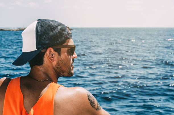 Man in a hat in a boat in the sea looking away at the sea