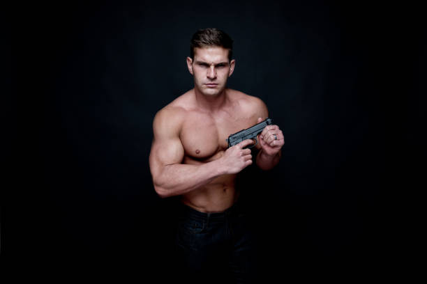 istock Shirtless muscular man holding a handgun 1140169563