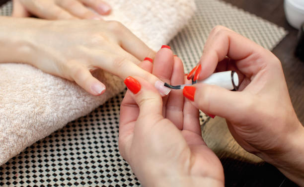 nail artist peint des ongles avec vernis à ongles pendant la procédure d’extensions d’ongle avec gel dans le salon de beauté. soin professionnel pour les mains. - acryle photos et images de collection