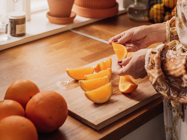 istock Woman cutting oranges and eating close up in kitchen 1140170590