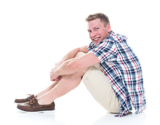 istock Handsome man in shirt and shorts is sitting side view 1140171229