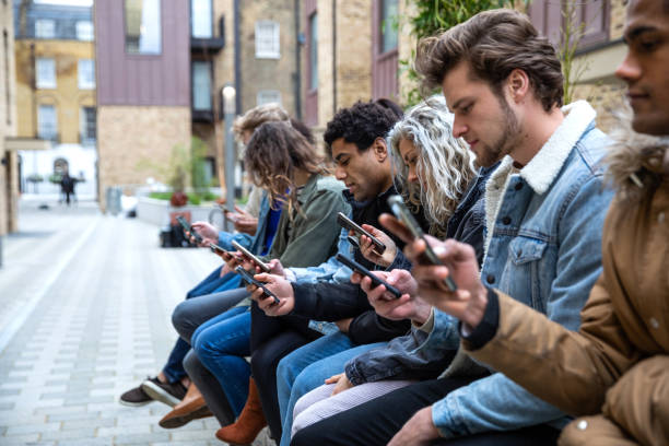 gruppo di amici adolescenti focalizzato sul proprio smartphone sms sui social media - addiction foto e immagini stock