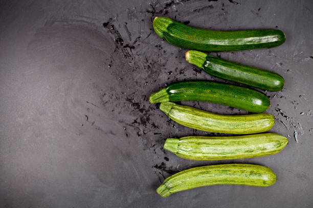 istock Fresh green wet zucchini on blackboard background. 1140176492