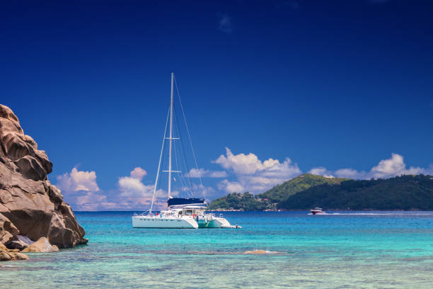 Catamaran near tropical beach Ship landing near Anse Severe on La Digue Island, Seychelles la digue island photos stock pictures, royalty-free photos & images