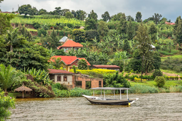 Roof boat anchored at the coast with Rwandan village in the background, Kivu lake, Rwanda Roof boat anchored at the coast with Rwandan village in the background, Kivu lake, Rwanda lake kivu stock pictures, royalty-free photos & images