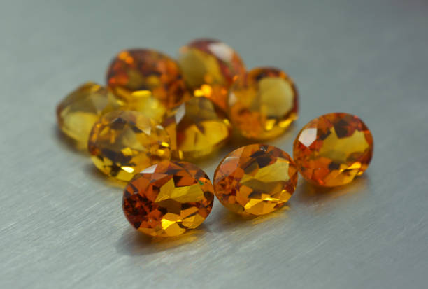 Group of ocher colored gemstones on metal surface Group of ocher colored gemstones on metal surface topaz stock pictures, royalty-free photos & images