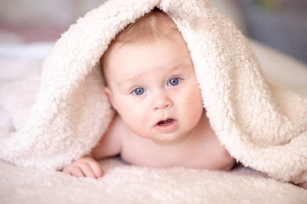 istock baby lying on a bed under towel 1140181557