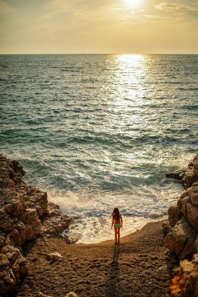 istock Girl standing alone on beach at sunset 1140181748