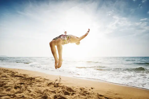 Man flips and spins a sommersault on the beach
