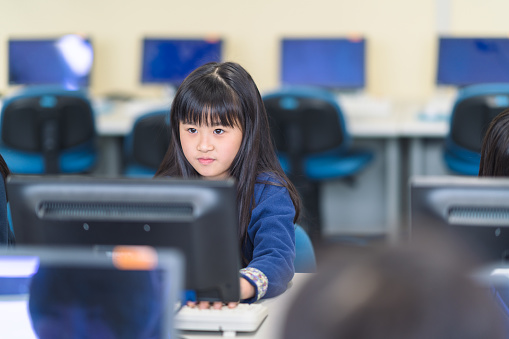 A group of elementary school children are learning to use computer at school.