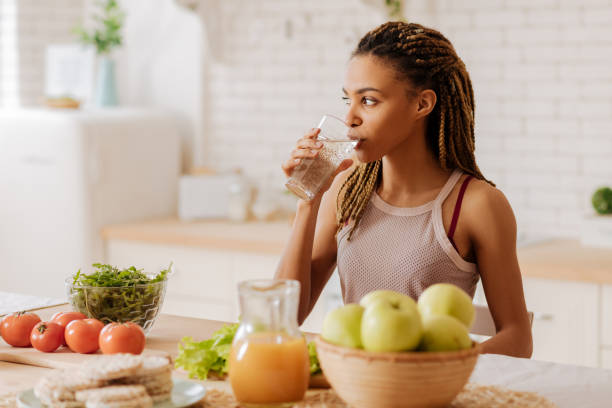 l’eau potable de femme mince et d’ajustement avant de prendre le petit déjeuner - fruit bodies photos et images de collection