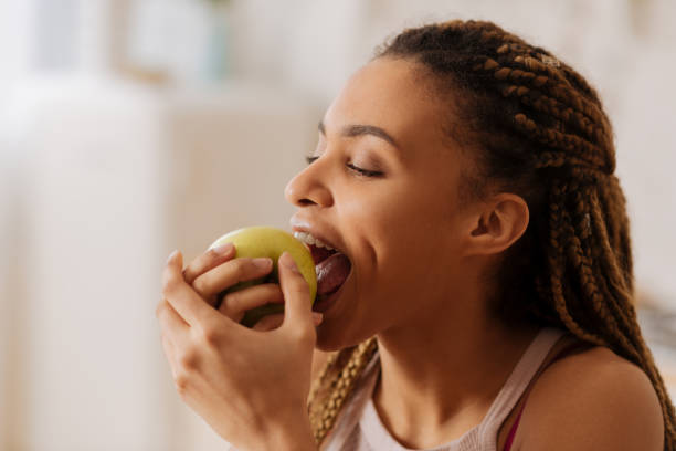 hermosa joven mujer mordiendo bonita manzana verde en la mañana - apple women green eating fotografías e imágenes de stock