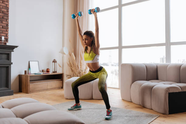 istock Appealing sportswoman raising her hands with blue barbells 1140193297