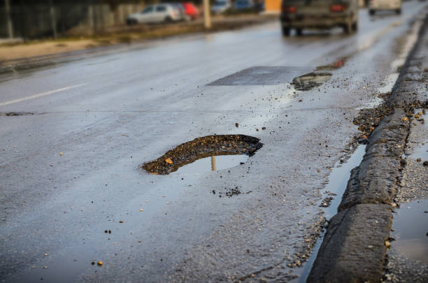 grande buca su strada dopo l'inverno - road street thoroughfare hole foto e immagini stock