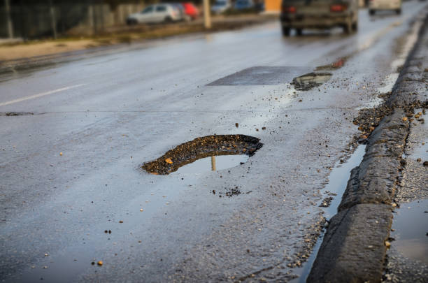 Big pothole on road after winter stock photo