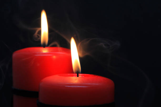 Three candles in candlestick and fireplace in background