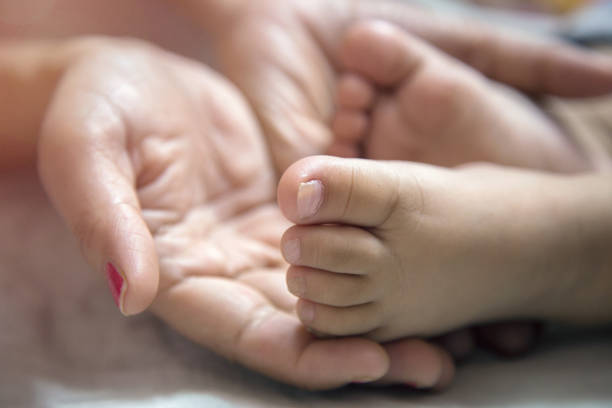 Close up Mother Holding Feet of infant Baby in Her Hand Close up Mother Holding Feet of infant Baby in Her Hand indian boy barefoot stock pictures, royalty-free photos & images