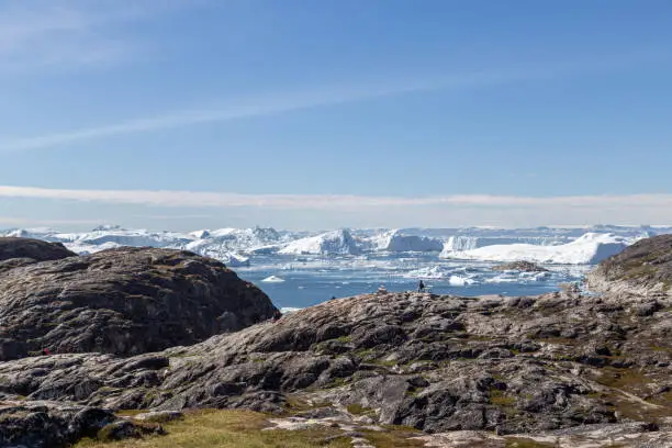 Ilulissat, Greenland - June 30, 2018: An unidentified tourist sitting at the Ilulissat Icefjord viewpoint