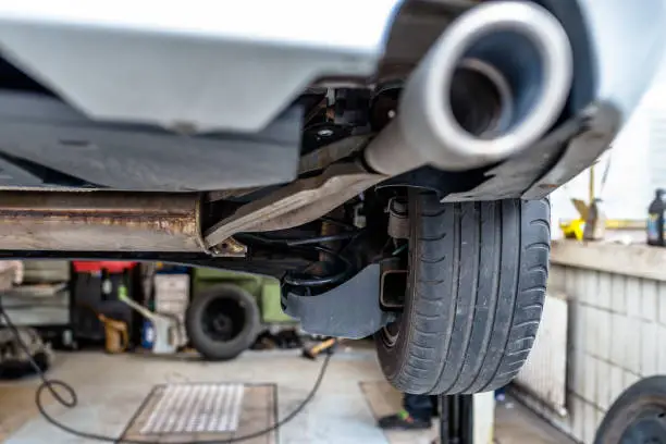 Photo of The exhaust system in the car seen from below, the car is on the lift in the car workshop.