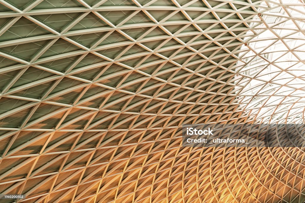 Il sole splende attraverso il tetto triangolato alla Kings Cross Station di Londra - Foto stock royalty-free di Architettura