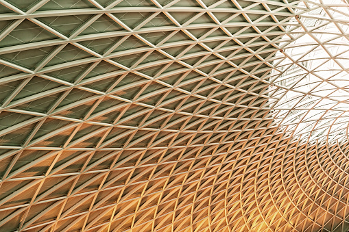 Sun shines through the triangulated roof at Kings Cross Station in London, United Kingdom