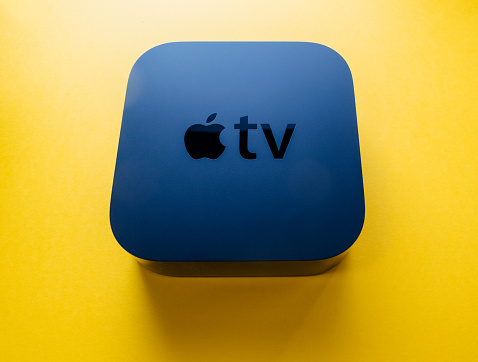 Paris, France - Nov 16, 2018: View from above at new black Apple TV 4K media streaming by Apple Computers  against yellow background - tilt-shift lens used
